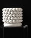 White 3D printed planter placed on a matching base, showcasing the lower curvature of the pot and deep interlocking pattern, with a softly diffused light accentuating the woven texture and sharp definition of each layered segment.