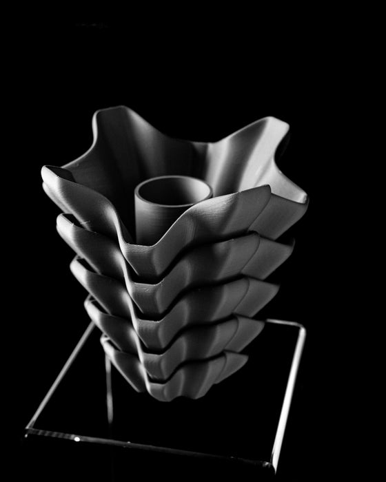 flower vase with dark black tone and cascading reliefs in modern design, sculptural black vase 3d printed with precision ridges and layered form, modern flower vase with personalized aesthetic and bold vertical shaping, unique gift or decor piece suitable for dried flowers or home office, vase for flowers with faceted modern details and striking contours