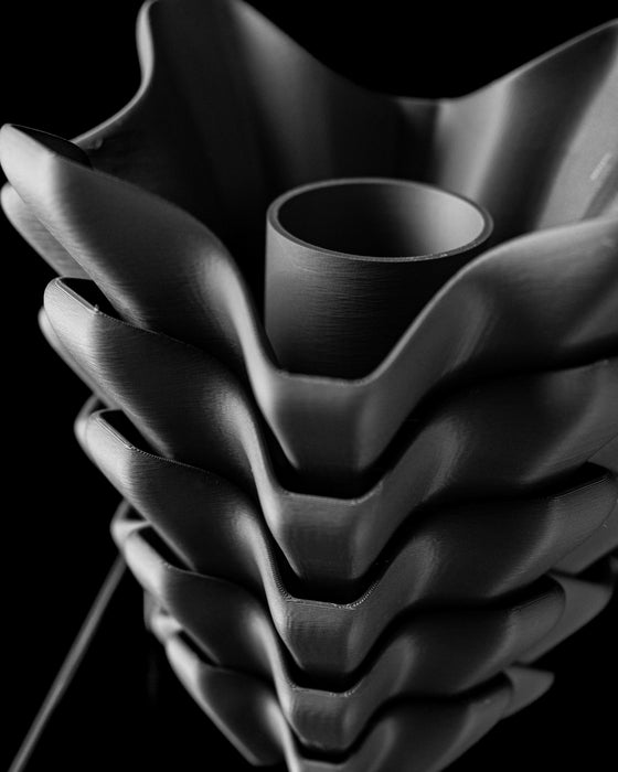 flower vase with dark black tone and cascading reliefs in modern design, sculptural black vase 3d printed with precision ridges and layered form, modern flower vase with personalized aesthetic and bold vertical shaping, unique gift or decor piece suitable for dried flowers or home office, vase for flowers with faceted modern details and striking contours