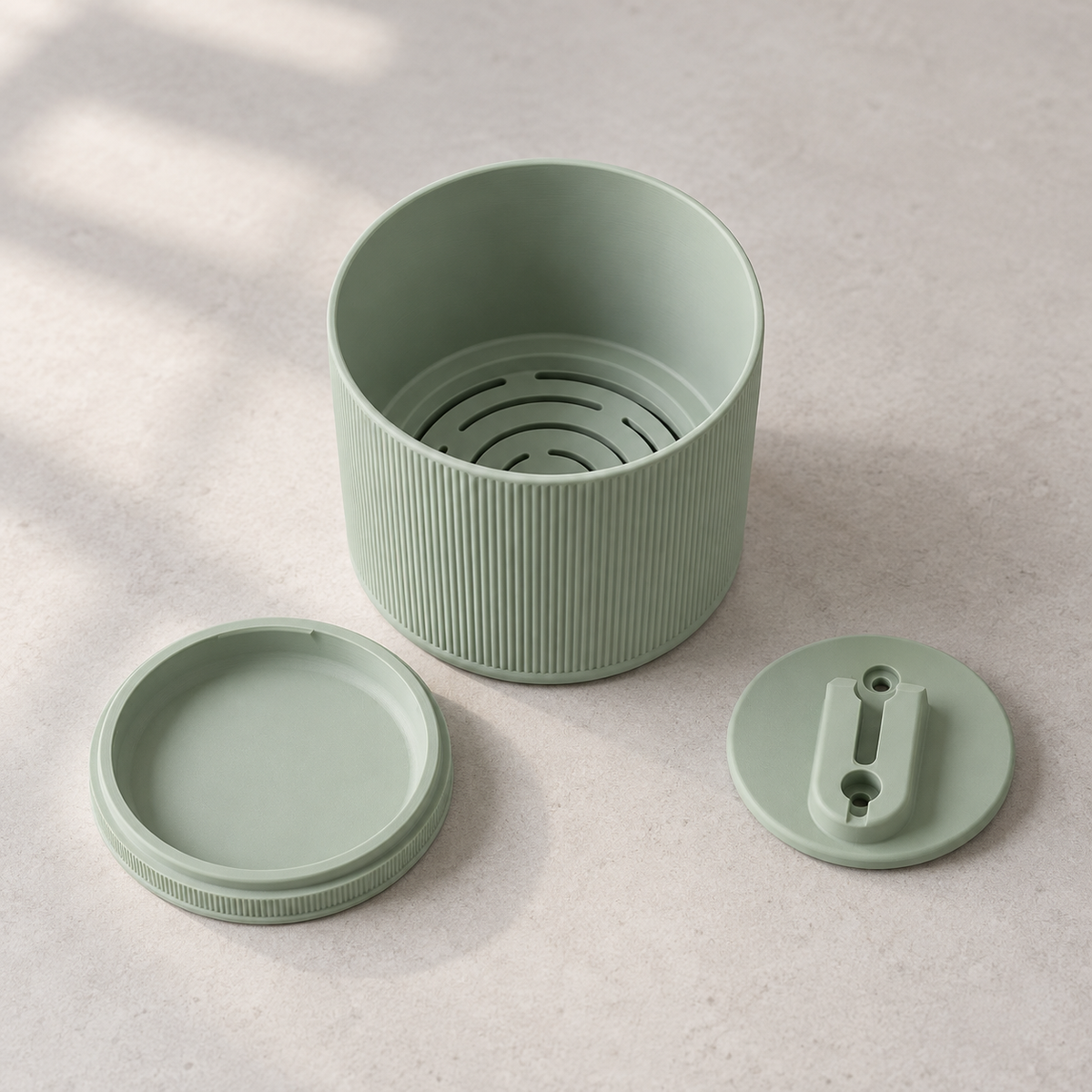 Green Tori wall planter parts showing curved drainage slots, a detached round base and a wall bracket.