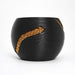 Angled reverse view of the black round planter, highlighting its shorter gold-tone inlay and flowing ridges