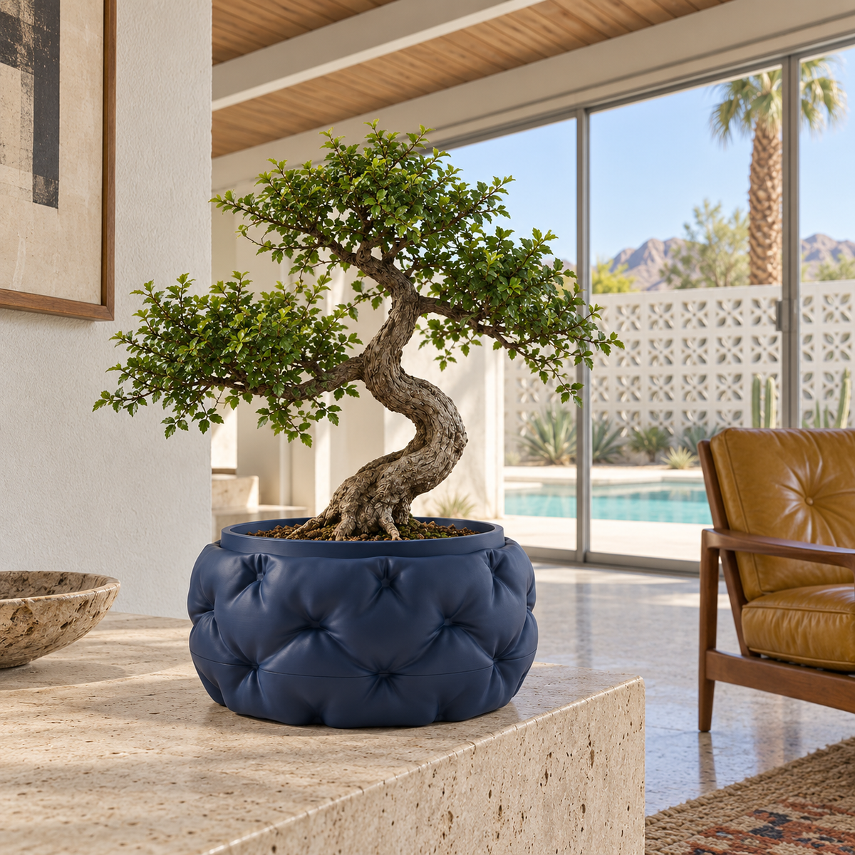 Leafy bonsai in a navy Kivu quilted planter on a light stone surface beside a large window.