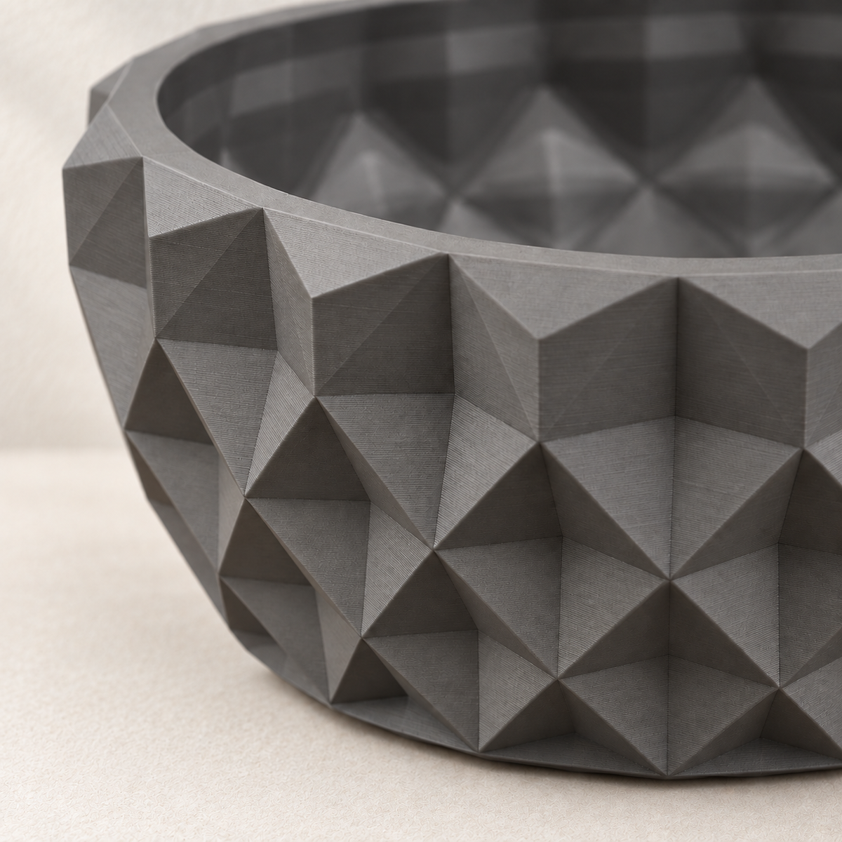 Close-up of the angular triangular facets and rim on a gray Prizma bonsai planter.