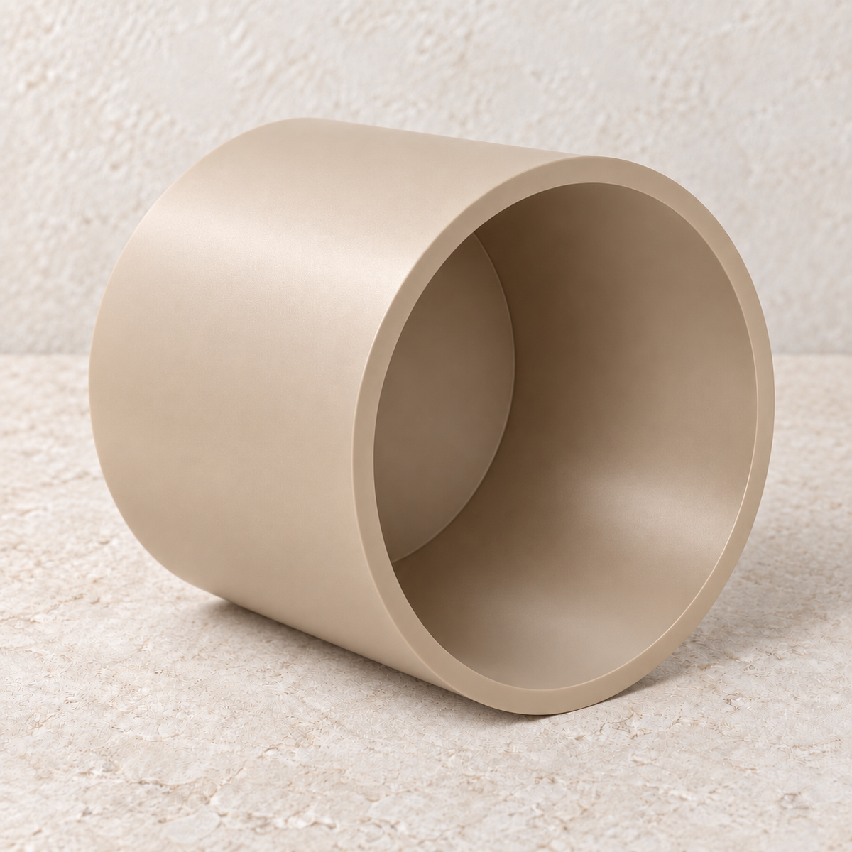 Beige cylinder plant stand resting on its side to show the open hollow underside and the thickness of its wall.