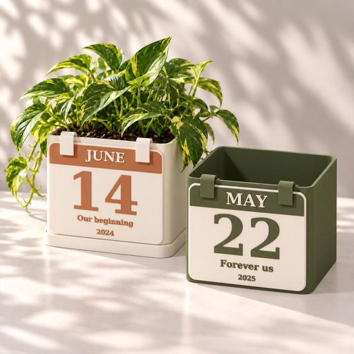 Two personalized calendar planters in cream and green with different dates; one holds a pothos plant.