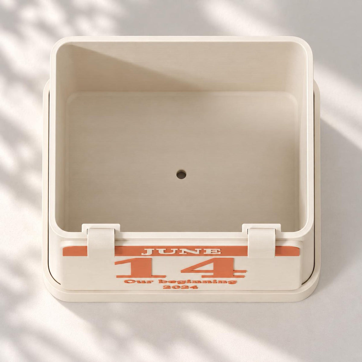Top view inside the rectangular planter showing its centered drainage hole and personalized front plaque.