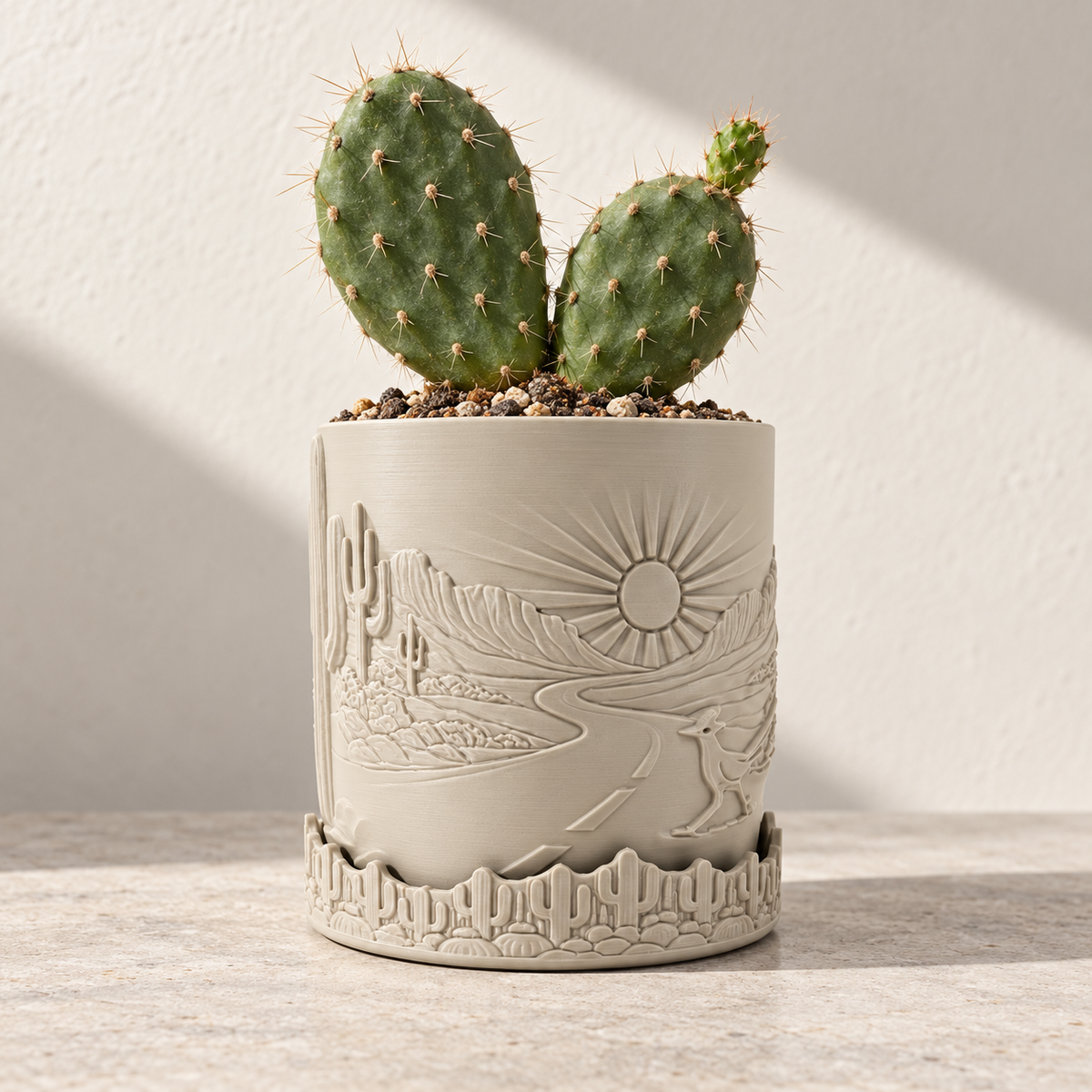 Cream Desert Sunrise planter with a raised sun, cactus and landscape scene beneath a cactus plant.