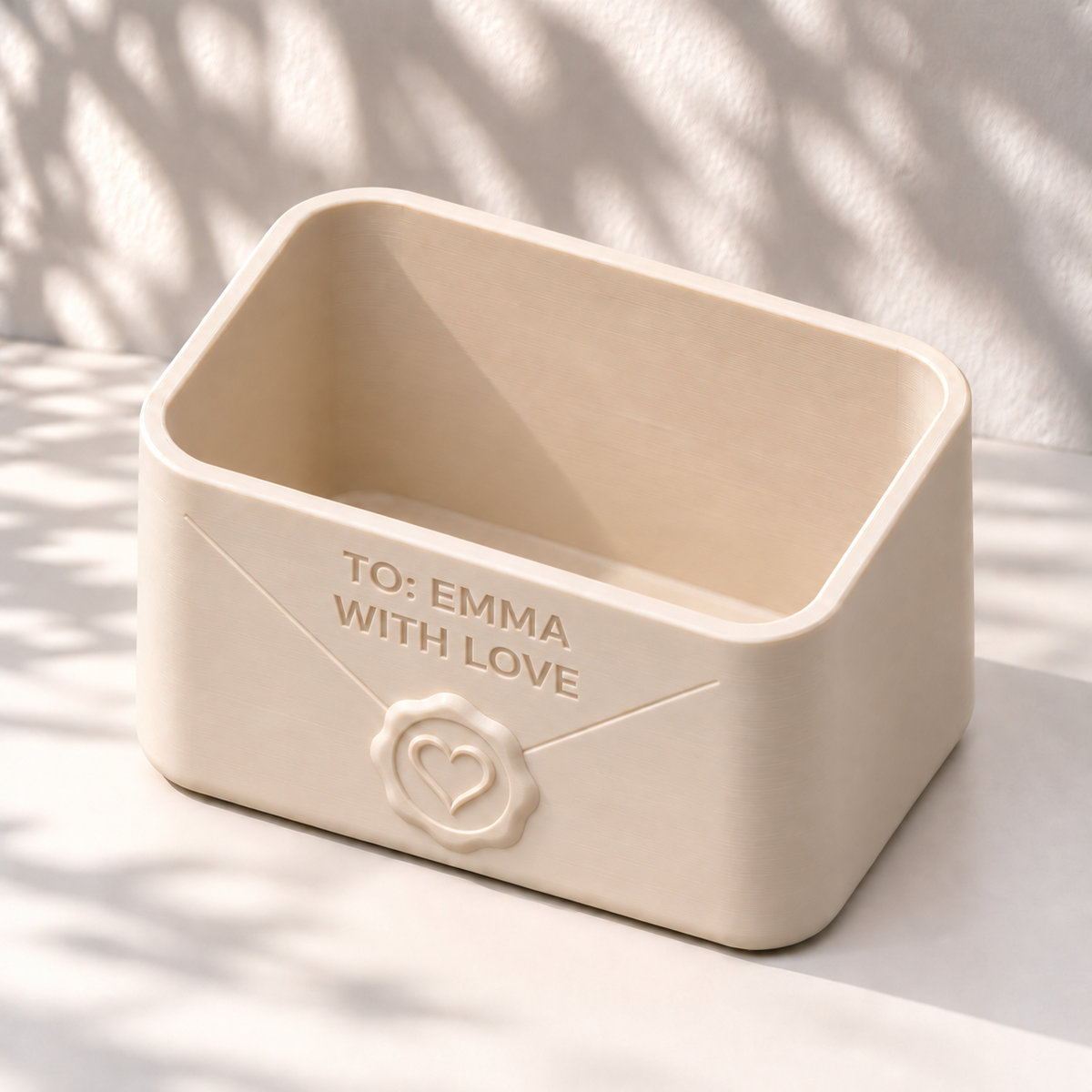Angled view of a cream Envio envelope planter showing its rectangular opening, rounded rim and personalized front.