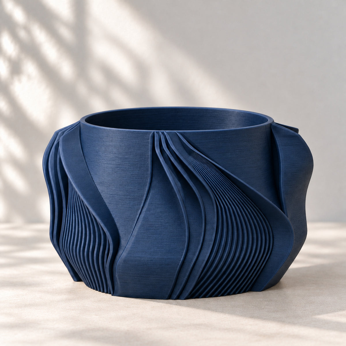 Empty navy blue Fano planter showing its round opening and sculptural fan-shaped exterior folds.