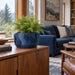 Navy blue Fano tabletop planter with foliage on a wooden cabinet beside a living room window.