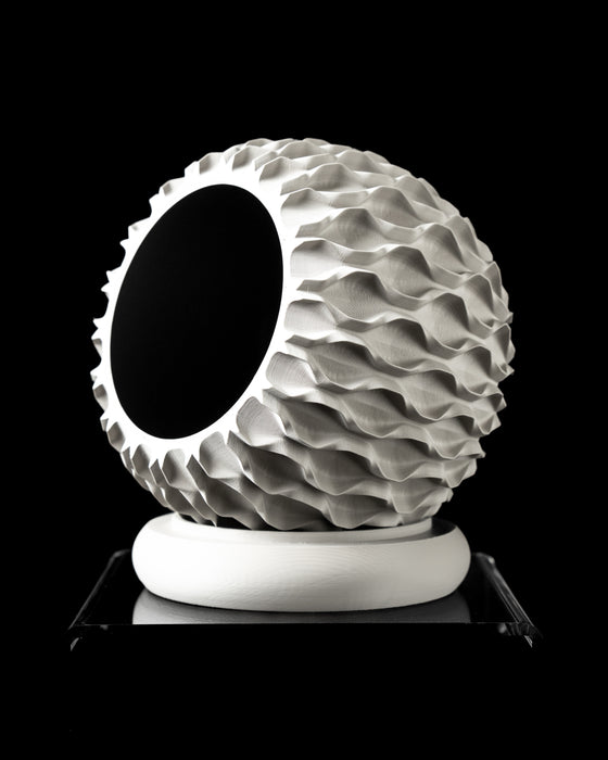 Macro view of the lower portion of a 3D printed planter, drawing attention to the network of polygonal cutouts on its cylindrical support ring. These hollowed cells are crafted to distribute weight while maintaining an airy architectural profile. The upper planter body features a muted texture with visible layer lines, creating a refined contrast with the sculpted base. Together, they form a striking visual rhythm of mass and negative space.
