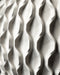 The planter is displayed in a tattooed hand, showcasing its size and scale relative to human touch. The top portion features a vertically brushed gray finish, subtly catching light, while the base remains boldly geometric, evoking a sense of balance between digital form and artisanal tactility. The solid matte finish complements the voided lattice, making this planter an expressive and functional decor item for any surface.