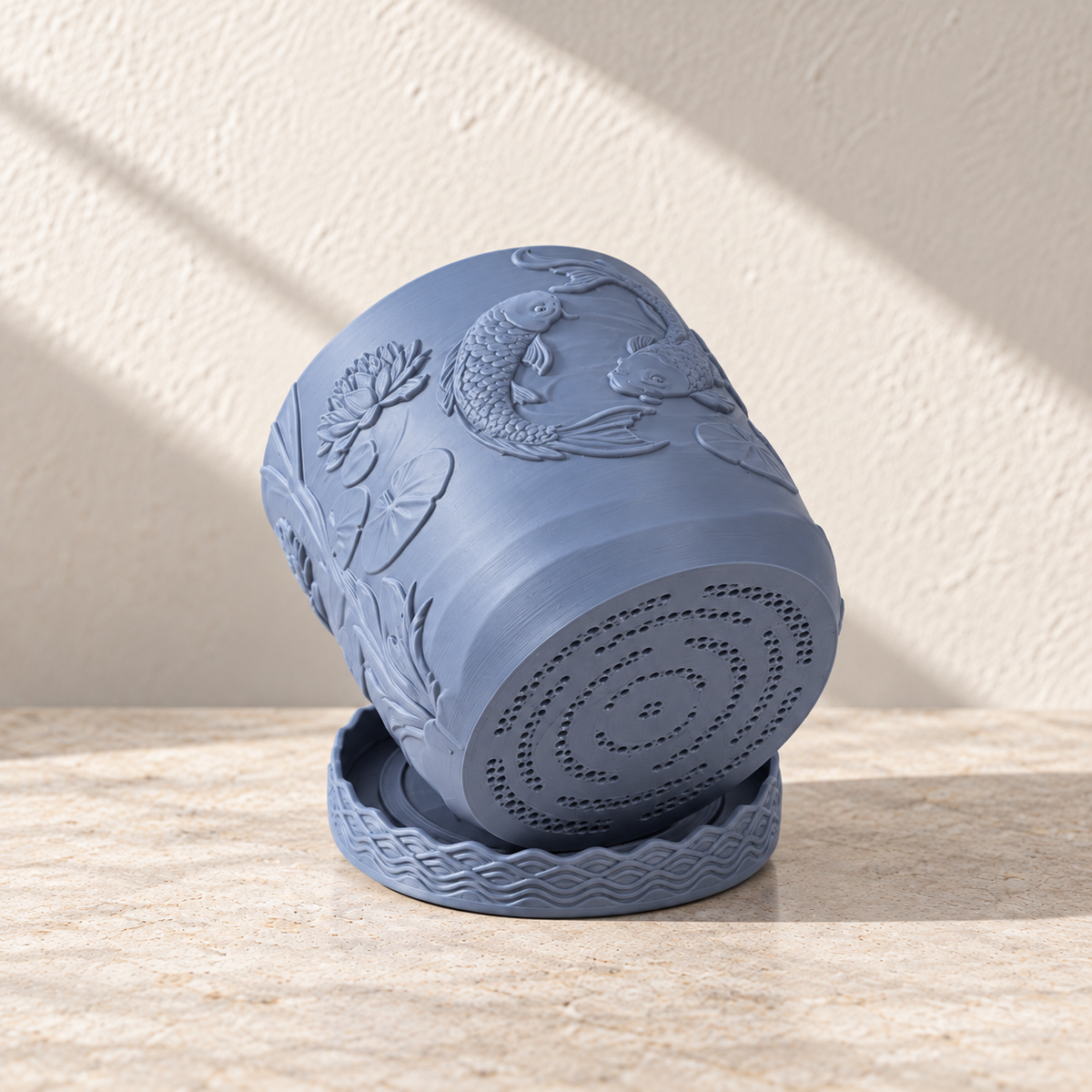 Blue Coraline planter tilted to reveal its perforated bottom while resting against the matching tray.