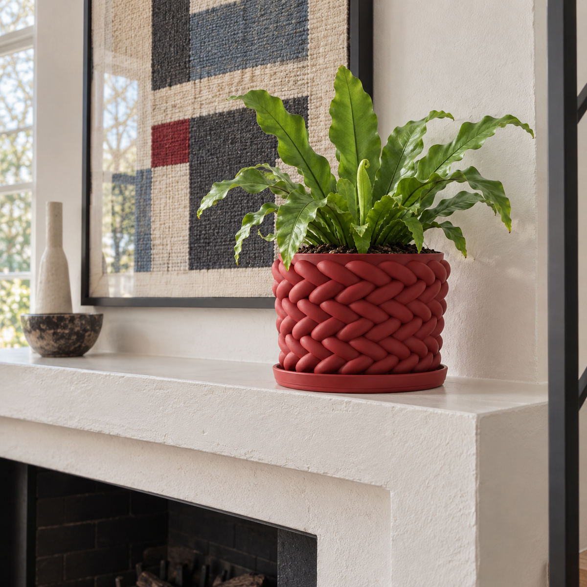 Red Braido woven planter holding a fern on a light mantel in a bright living room.