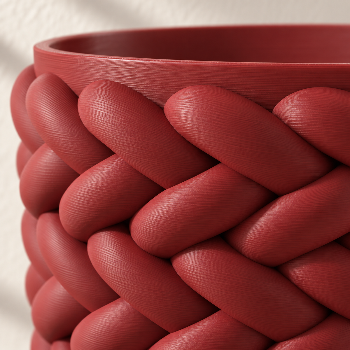 Close-up of the thick overlapping braid relief and upper rim on a red Braido planter.