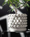 Modern white 3D printed planter with lush green plant, placed on sleek pedestal; clean lines, consistent weave texture, and a smooth base make this planter a standout piece for contemporary decor.