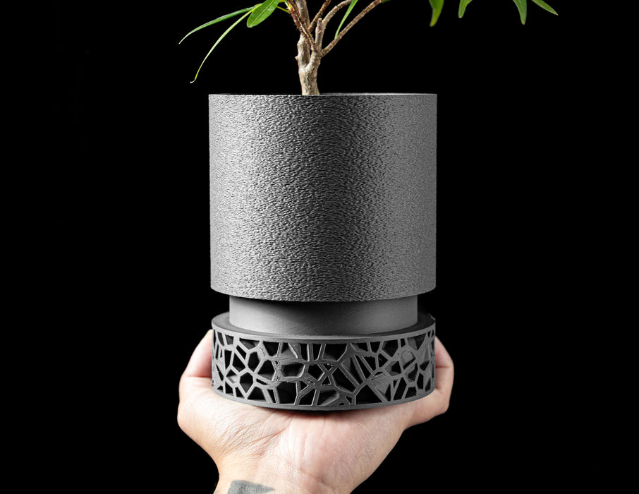 side profile of matte black planter with minimalist cylindrical shape and finely layered texture, designed for elegance and function, standing on an open-patterned architectural base inspired by natural bone structures, 3d printed with eco-friendly PLA, blending art and utility, planter pot, 3d printed planter, decorative flower pot, sculptural container, minimalist planter design, modern texture, interior decor object, housewarming gift, personalised home piece, new home accessory