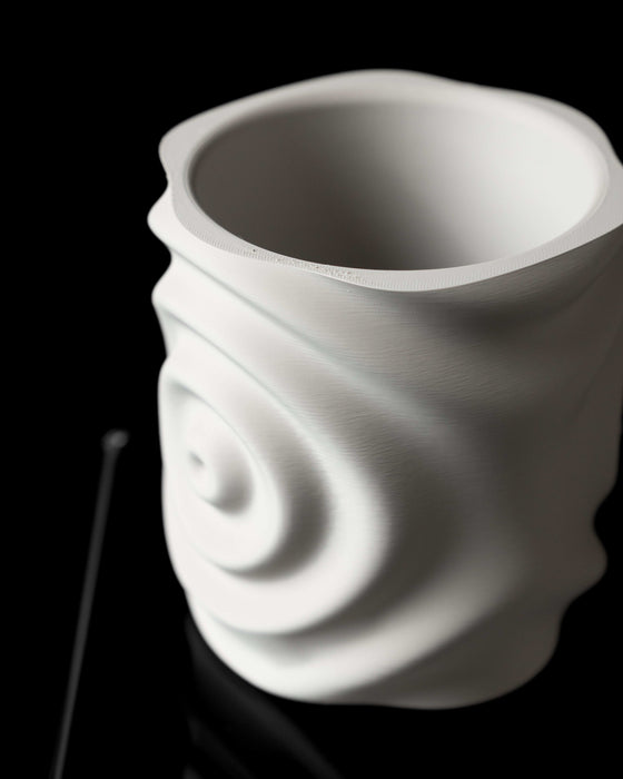 white 3d printed flower pot viewed from side with centered ripple indent and organic distortions in form, artistic rendering of liquid motion captured in plastic, sculptural object functioning as planter, visually balanced and digitally manufactured, smooth matte finish emphasizes layered printing texture, suitable for succulents or houseplants, futuristic and minimal in silhouette