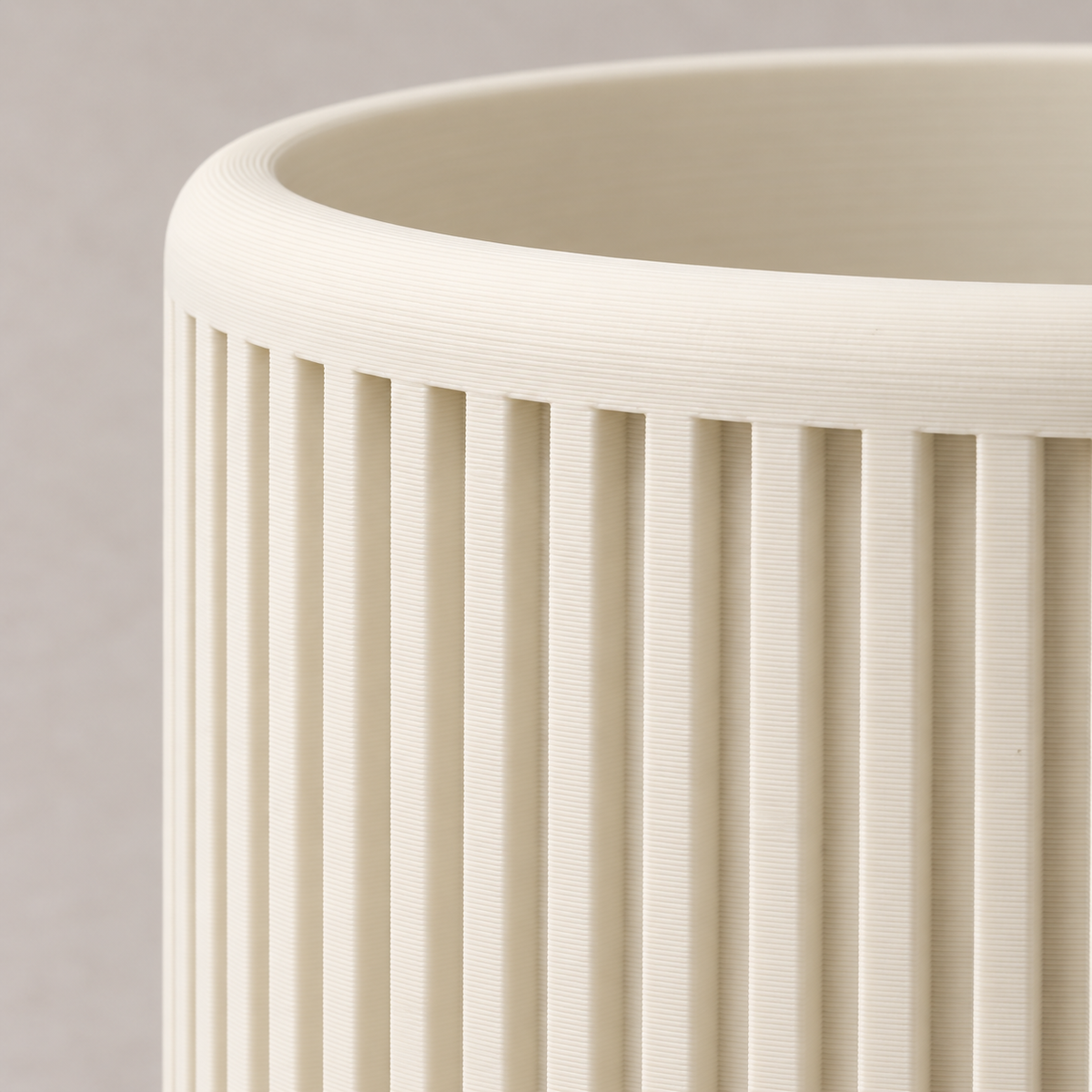 Close-up of the deep vertical ribs and smooth upper rim on a cream Quadra planter.