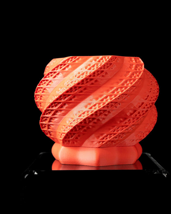 Bright red 3D printed flower pot with intricate spiral textures, displayed in hand. Designed as a unique planter for succulents or indoor plants, it blends modern art with functionality. Perfect for use as a book plant pot, a decorative indoor planter, or low planter pot. A memorable and artistic choice for unique home decor and great gifts for mom or any plant lover.