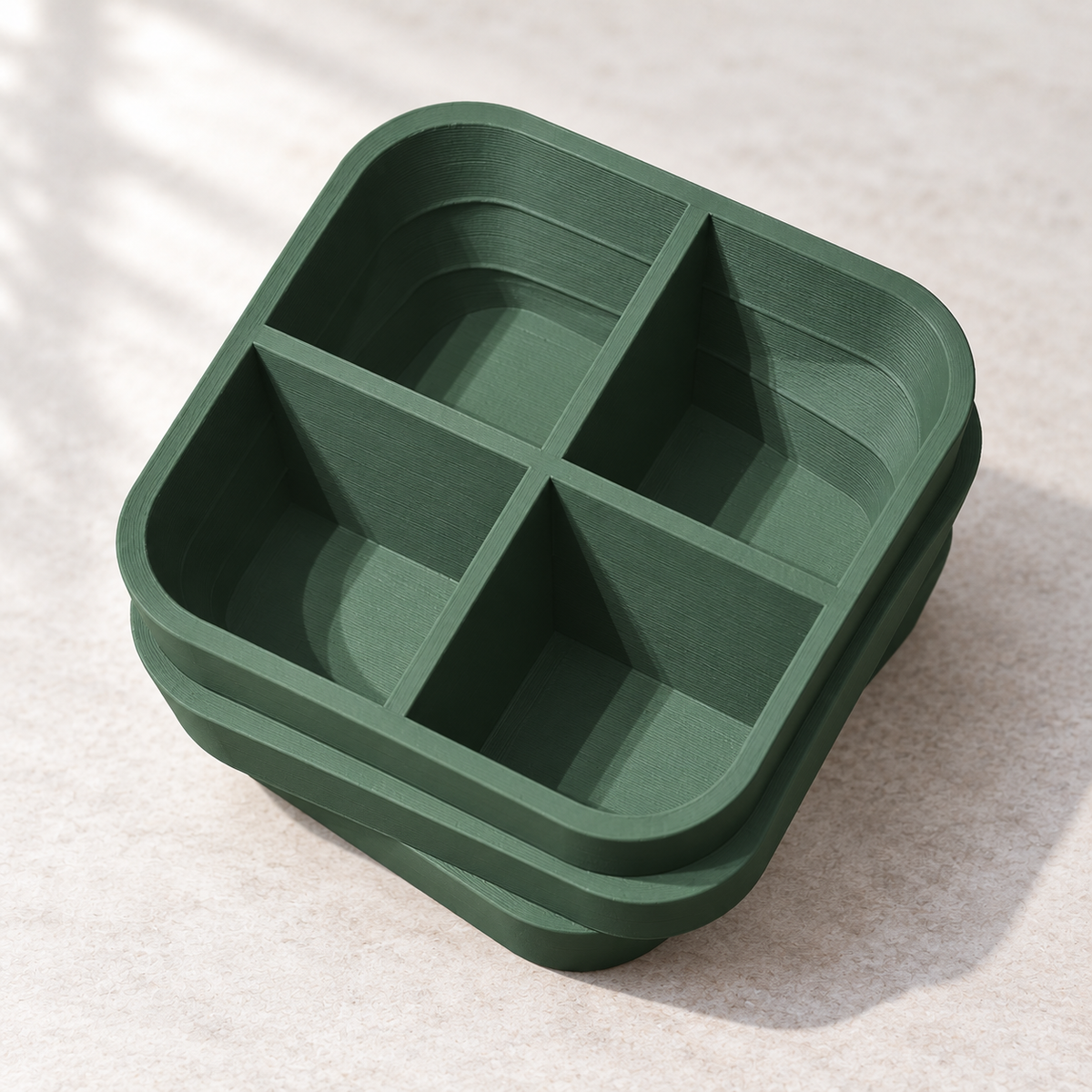 Underside of a green plant stand showing four open cavities, crossing partitions and sloped inner walls.