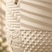 Close-up of Tessaro's cream woven panels, diagonal ridges, raised dots and crackle relief, with fine print layers and the removable saucer seam.