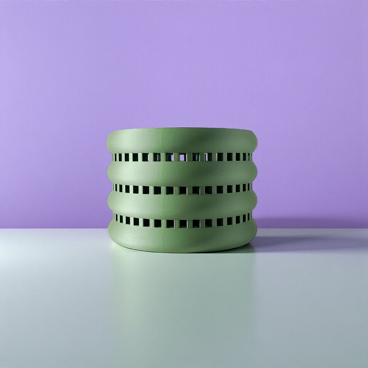 Ulra ventilated orchid pot with horizontal bands, front view against a purple background
