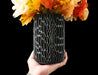 black cylinder-shaped flower vase made with 3d printing technique, showing deep oval indentations forming a dense pattern, ideal vase for dried flowers or tall decorative arrangements, artistic vase design with sculptural texture, modern black vase with perforated surface for unique gift or stylish accent, flower vase with vertical openwork structure, minimalist futuristic vase, ikebana vase, aesthetic vase, black vase, unique home decor, home office vase