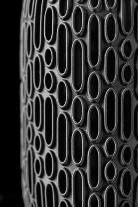 close-up of 3d printed black vase with raised oval grid pattern and matte finish, showcasing intricate craftsmanship and futuristic surface detail, artistic vase with sculptural cutouts and solid core, designed for dried flowers or ornamental stems, modern black cylinder vase with dimensional texture and minimalist style, flower vase, black vase, 3d printed vase, modern flower vase, vase dried flowers, unique home decor