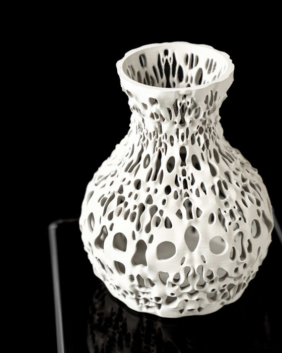 White sculptural vase with a bulbous body and sharply narrowing neck, featuring a dramatic open lattice of irregular holes inspired by cellular patterns; its layered 3D-printed surface subtly reveals the additive manufacturing process, enhancing tactile and visual depth; perfect for dried flowers, decorative stems, or curated floral arrangements, especially in modern or conceptual interiors.