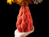 angled view of red-orange vase with flame-like textured body and narrow top opening, perfect for decorative dried flowers