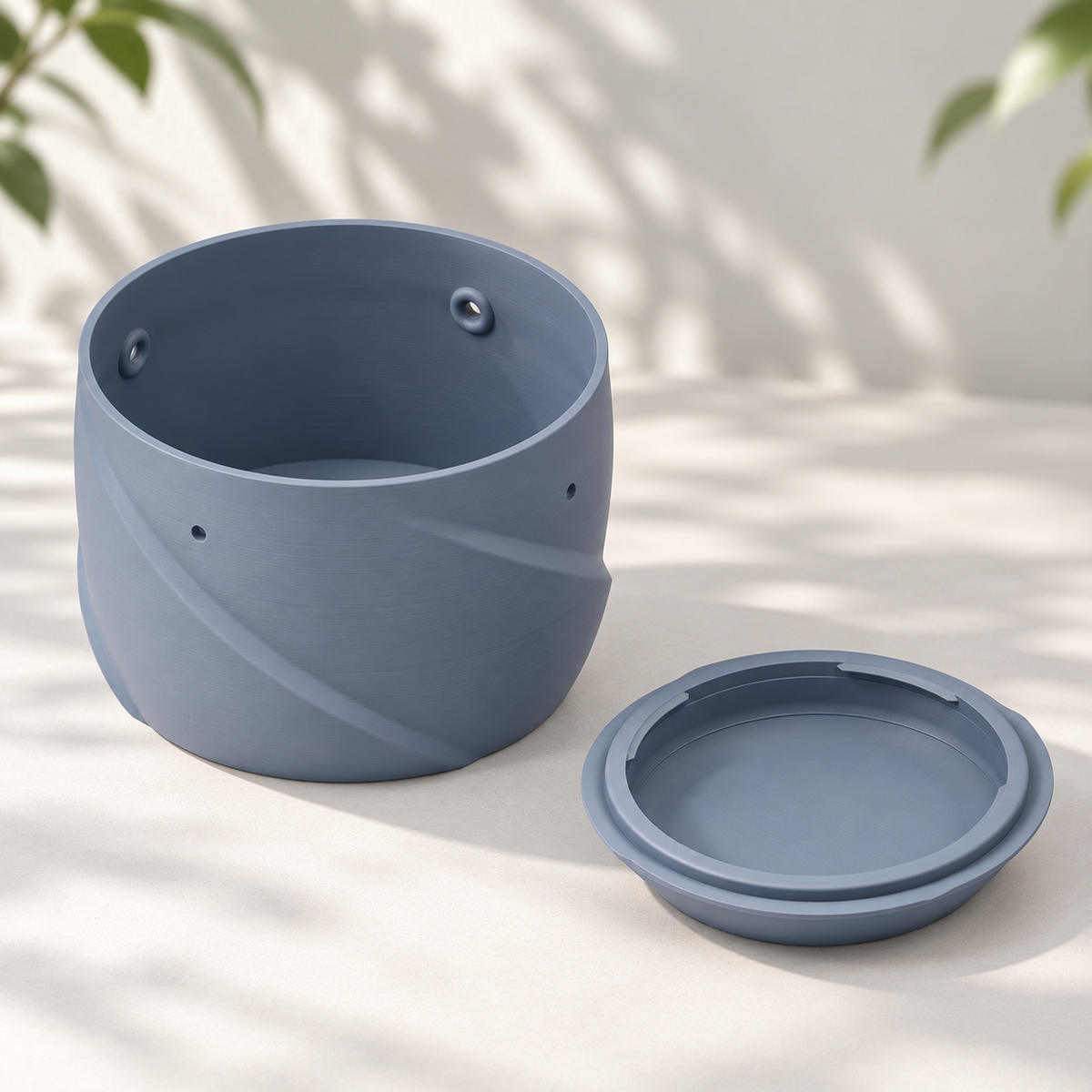 Grey Blue hanging planter beside its detached twist-off water collector on a pale surface.
