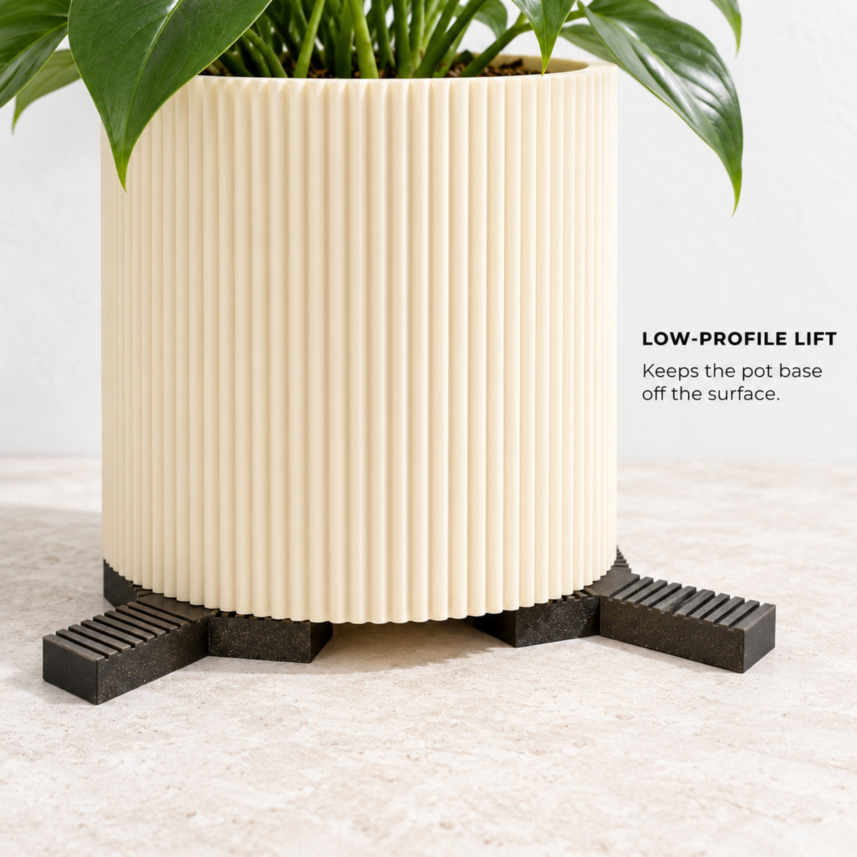 Close-up of a planter lifted slightly above a stone surface on separate Trivio plant pot feet.