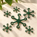 Six green 3D printed plant stem supports in varied sizes on a light stone surface