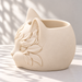 Side view of the cream white cat planter showing sculpted leaves and the rounded textured body
