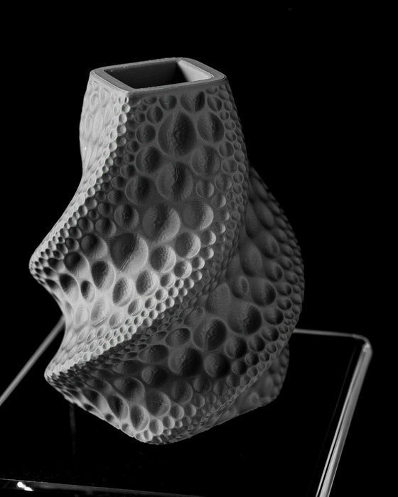 3d printed black vase with cratered structure and elegant vertical ridges, flower vase with distinct lunar surface pattern and cylindrical foundation, black vase ideal for dried flowers or curated decorative stems, personalized vase with moon-inspired sculpting and modern silhouette, black modern flower vase with crater-textured body and softened lip, aesthetic vase for home office or design-forward interiors, sculptural vase with dimensional reliefs and tactile form, home office decor with lunar influence,