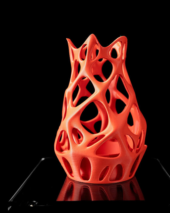 3d printed orange vase held in hand, featuring smooth biomorphic holes and twisted structure, modern flower vase with sculptural design for dried flowers or decorative stems, personalized vase ideal for unique home decor, vase for dried flowers and curated floral arrangements, lightweight and visually striking organic form with complex symmetry