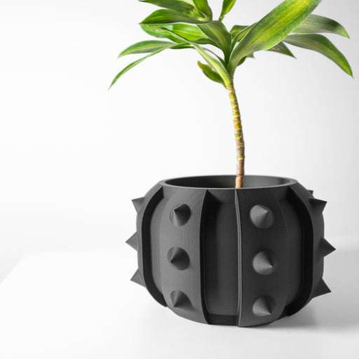 Black 3D printed planter pot with wide geometric body and vertical groove running down the front, featuring spherical protrusions on each side