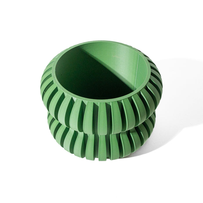 Artistic planter with curved green body, combining sculptural impact and functional drainage for bold tabletop arrangements