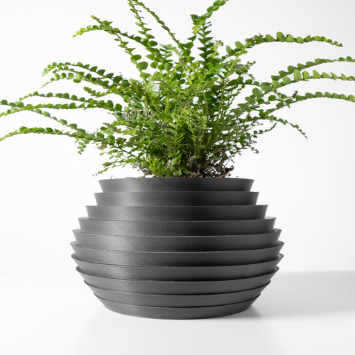 Matte black 3D printed planter pot with wide horizontal grooves and round silhouette tapering toward the base
