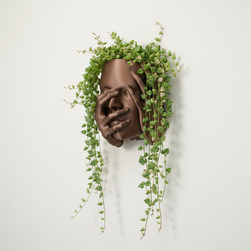 Echo wall planter mounted on wall with trailing pothos plant, sculptural face and hands design