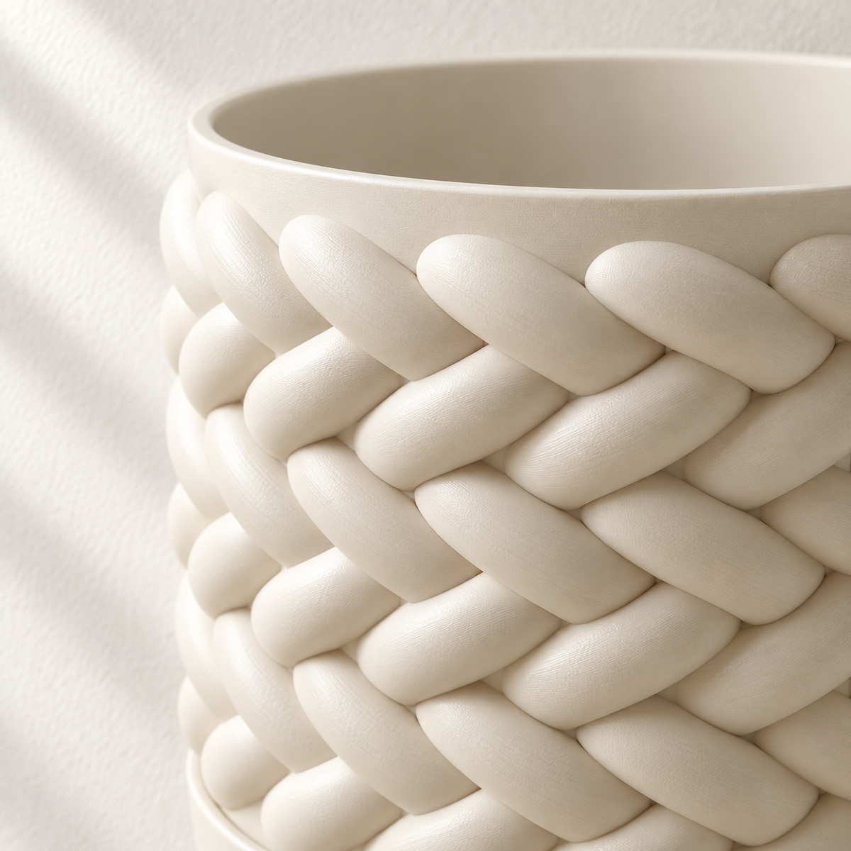 Close-up of the cream Braido wall planter showing raised overlapping strands around the open rim.