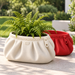 Ivory Large ASA Zipra pouch planter with fern in front of red Medium planter on an outdoor patio; one planter per order